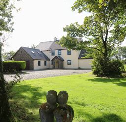 A detached house with a garage surrounded by lawn and trees at Mountain Farm in Broad Haven