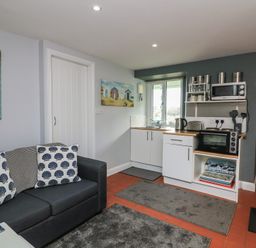 A kitchen with a sofa and wall art at Hidden Treasure in Brixham