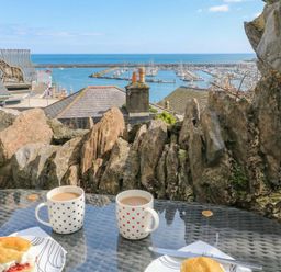 An outdoor scene with coffee cups and scones overlooking a marina at Hidden Treasure in Brixham