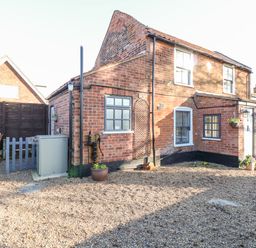 A brick house with multiple windows flower pots and a gravel yard at Foundry Cottage in Reedham