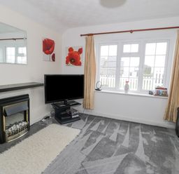 A living room with a fireplace television and window with curtains at Halcyon Annexe in Moelfre near Benllech