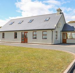 A single-story house with a pitched roof skylights multiple windows and a lawn at Dooneen near Castletownshend County Cork