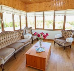 A sitting room with vintage sofas a wooden coffee table a vase with flowers and large windows at Dooneen near Castletownshend County Cork