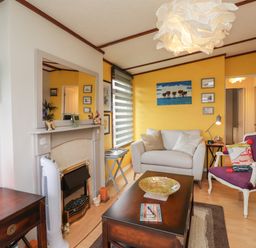 A living room with a fireplace beige sofa purple armchair and dark wooden coffee table at 4 Country View Park in Graveney near Seasalter