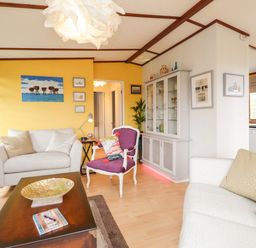A living room with white sofas a purple chair a wooden coffee table a glass cabinet and yellow walls at 4 Country View Park in Graveney near Seasalter