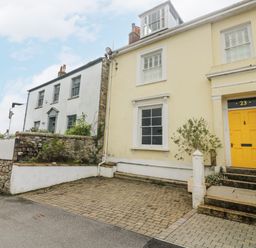 A row of attached houses with stone and brick walls and a yellow door numbered 23 at The Water House in Falmouth
