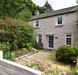 A stone cottage with a small garden and paved patio at Milkwood Cottage in Fishguard Pembrokeshire