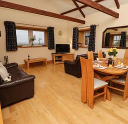 A living room with a sofa and dining table at Stable D'or in Embleton