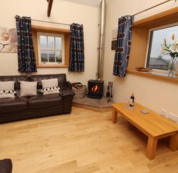 A living room with a sofa and a fireplace at Stable D'or in Embleton