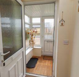 A conservatory with a door, window, and a vase at The Retreat in Embleton