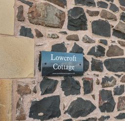 A stone wall with a sign reading Lowcroft Cottage at Low Croft in Embleton