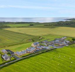 An aerial view of stone buildings surrounded by fields with grazing cows near the coast at Low Croft in Embleton
