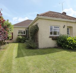 A yard with grass and plants around a beige house with windows at Downs View in Norton Ferris
