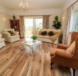 A living room with armchairs a sofa coffee table and wooden flooring at Downs View in Norton Ferris