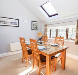 A dining room with a wooden table and four chairs under a skylight at Spring Cottage in Ambleside