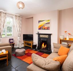 A living room with a fireplace television and couches at Dormouse Cottage in Coniston
