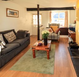 A living room with a sofa, armchair, and television at Buttonhole Cottage in Ambleside