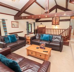A sitting area with three brown leather sofas and blue cushions at Old Coach House Ambleside