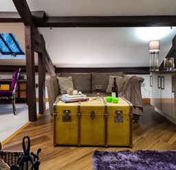 A living area with a sofa a yellow trunk used as a coffee table and a dining table with a purple chair at Hayloft in Windermere