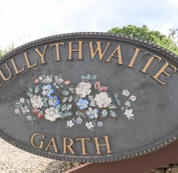An oval metal sign with floral design and the words Tullythwaite Garth in Crosthwaite