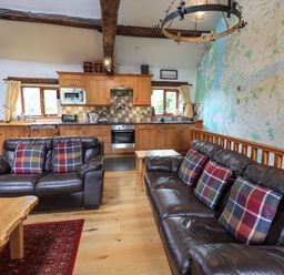 A kitchen and living area with brown leather sofas and plaid pillows at Tullythwaite Garth in Crosthwaite