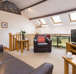 A living room with leather sofas wooden tables TV and skylight windows at Nest Barn in Keswick