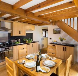 A kitchen with dining table and wooden beams at Nest Barn in Keswick