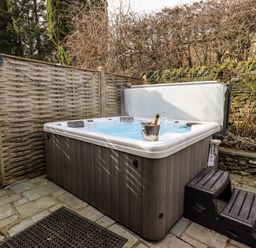 An outdoor hot tub with steps and a champagne bottle in an ice bucket at Hart Head Barn in Rydal