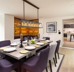A dining room with a set table and six purple chairs at Underhowe in Grasmere