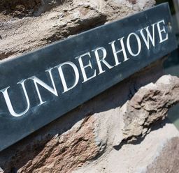 A close up of a sign reading Underhowe attached to a stone wall at Underhowe in Grasmere