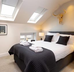 A bedroom with a double bed two skylight windows bedside lamps and a wall decoration at Underhowe in Grasmere