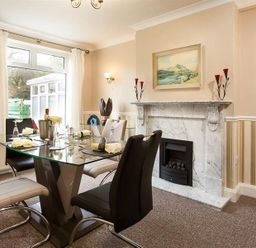 A dining room with a glass table and chairs near a fireplace at Heathfield in Keswick