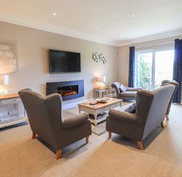 A living room with armchairs coffee table fireplace and television at Pure Grace in Ambleside
