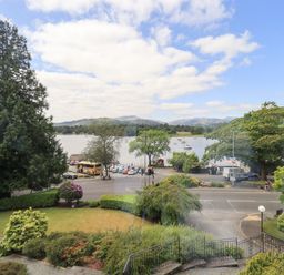 A view of a lake with boats trees a road and parked vehicles at Pure Grace in Ambleside