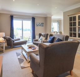 A living room with gray upholstered sofas a coffee table and a glass-front cabinet at Pure Grace in Ambleside