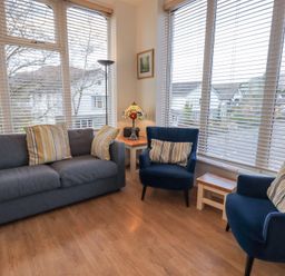 A seating area with a gray sofa and two blue armchairs with striped cushions at Windows in Ambleside