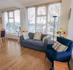 A living room with a blue sofa and armchairs and a dining table with chairs at Windows in Ambleside