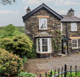 A house with a stone exterior and windows at Newby Bridge House in Newby Bridge