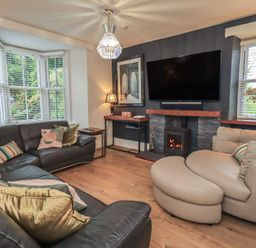 A living room with a sofa and television at Newby Bridge House in Newby Bridge