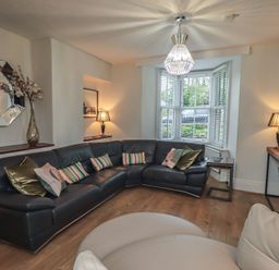 A living room with a sectional sofa and a lamp at Newby Bridge House in Newby Bridge