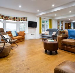 A living room with various sofas armchairs and a wall mounted TV at Wynford in Ambleside