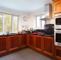 A kitchen with wooden cabinets black countertops and stainless steel appliances at Beech View in Ambleside