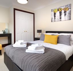 A bedroom with a bed linens and towels bedside tables lamps and a painting at Beech View in Ambleside