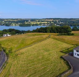 A rural landscape with a road a house fields trees and a lake in the background at Hawkrigg Farm Hawkshead