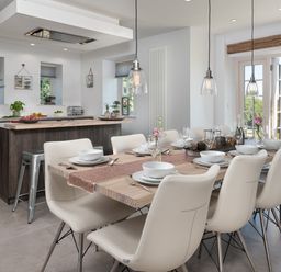 A dining area with a wooden table set for twelve and a kitchen with an island and stools at Hawkrigg Farm in Hawkshead