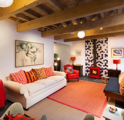 A living room with a white sofa red armchair and fireplace at Kentmere Hall Bank Barn in Kentmere