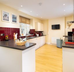 A kitchen with white cabinets dark countertops and wooden flooring at Scots Pine in Keswick