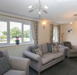 A living room with sofas and windows at Woodside West in Bowness