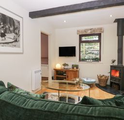 A living room with a wood stove and television at Corner Cottage in Troutbeck