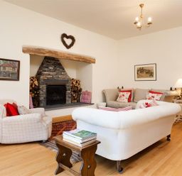 A living room with a stone fireplace sofas armchair and wooden floor at The Old Coach House in Troutbeck